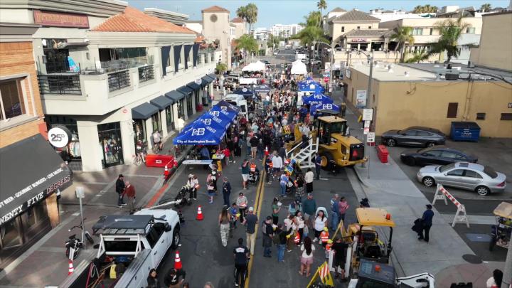 Downtown Huntington Beach aerial view with tents and a crowd surrounding tractors and other Public Works equipment.